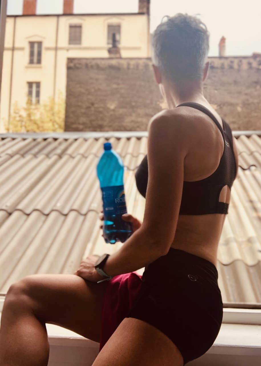Femme assise avec une bouteille d'eau à la main.