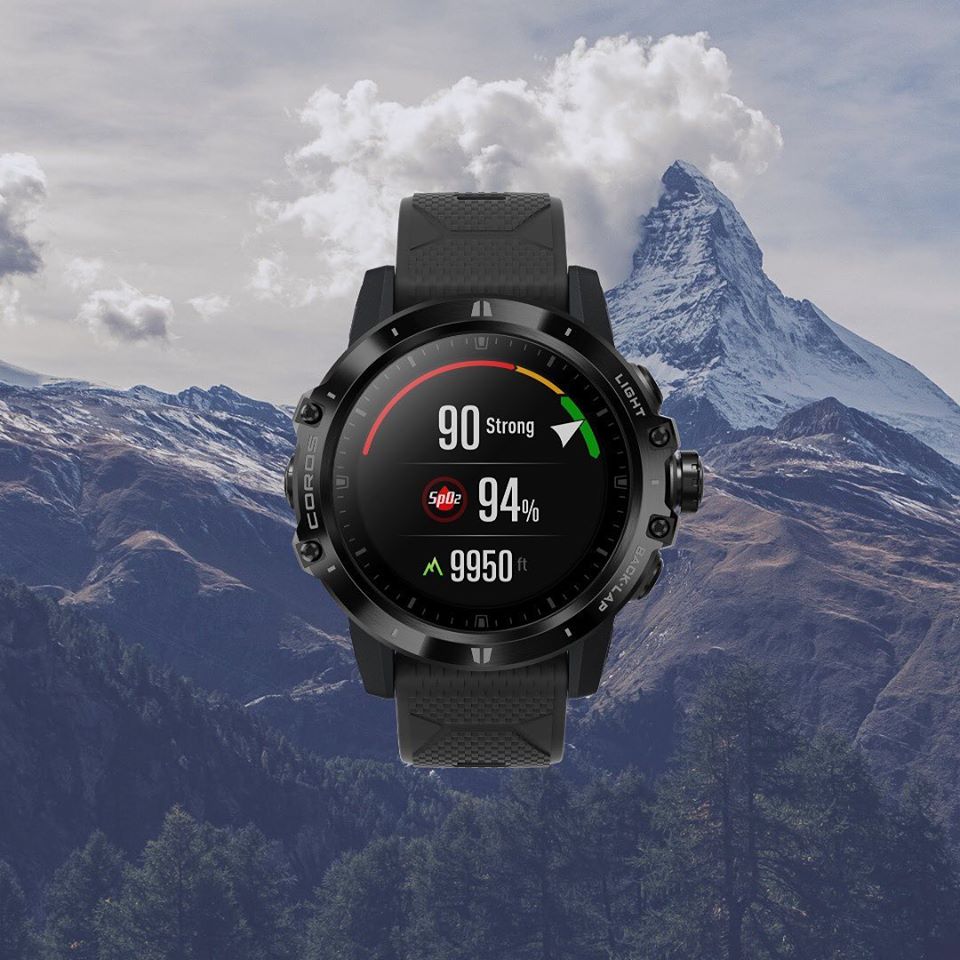 montre coros apex pro noir en avant plan, et des montagnes en arrière-plan.