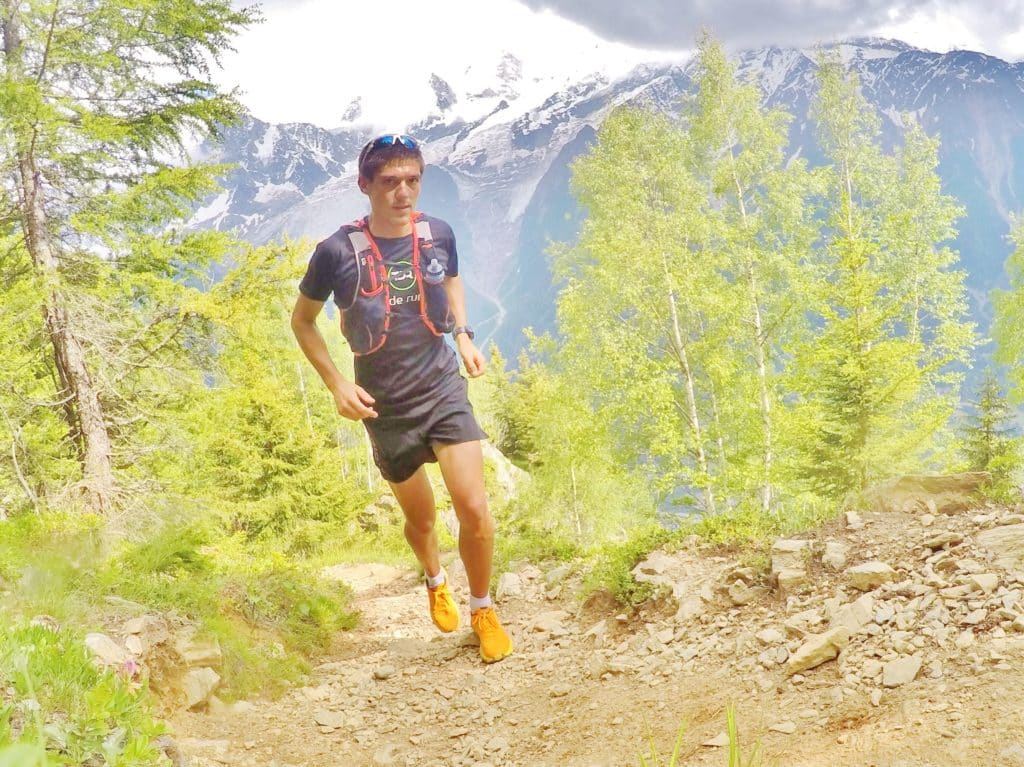 Coureur sur un sentier avec les montagnes en arrière-plan.