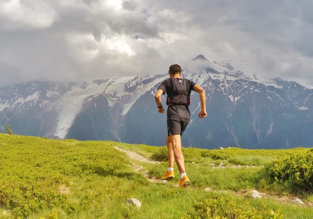 Coureur sur un sentier avec les montagnes en arrière-plan.